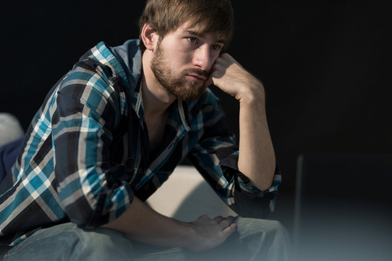 Young unemployed man sitting on the sofa