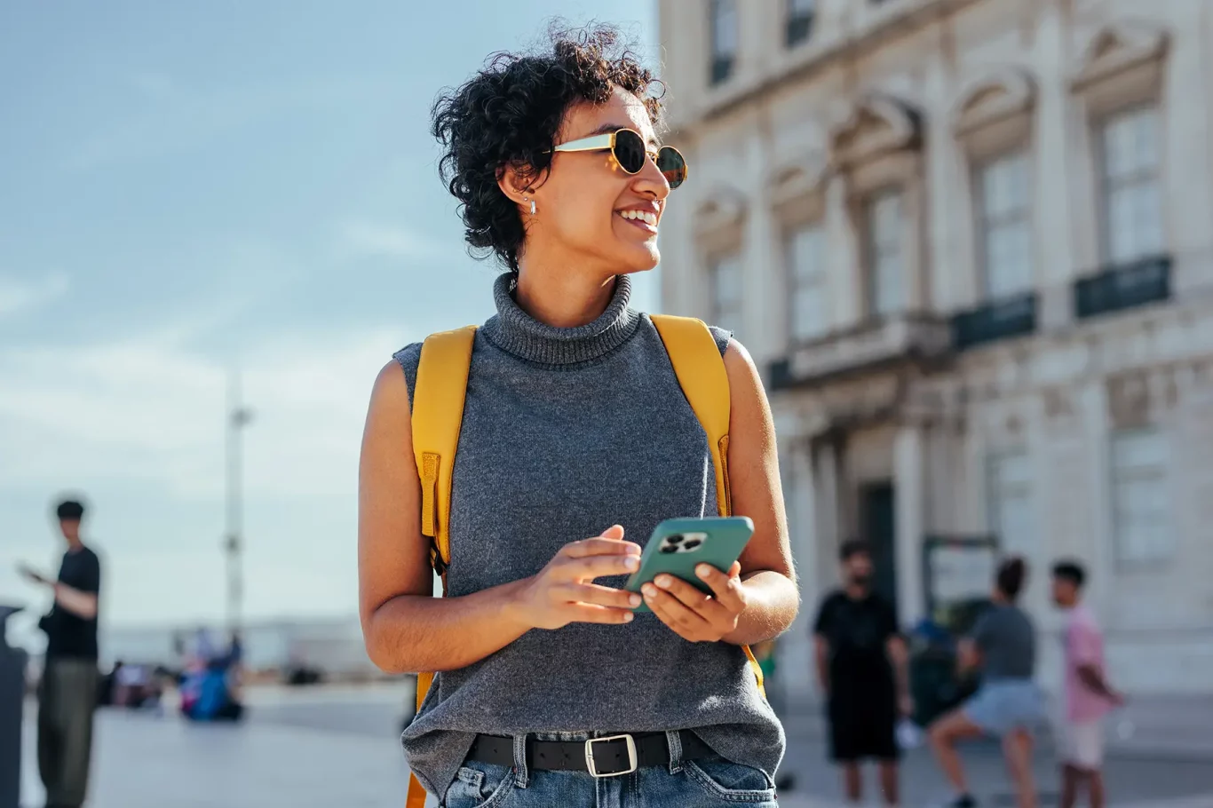 Young woman tourist with backpack using smart phone and exploring city during summer vacation