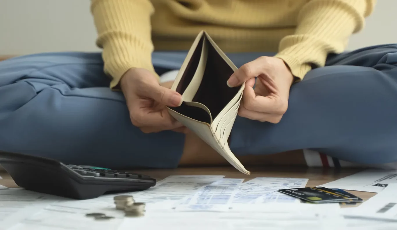 The stressed person sitting on the floor opening empty wallet