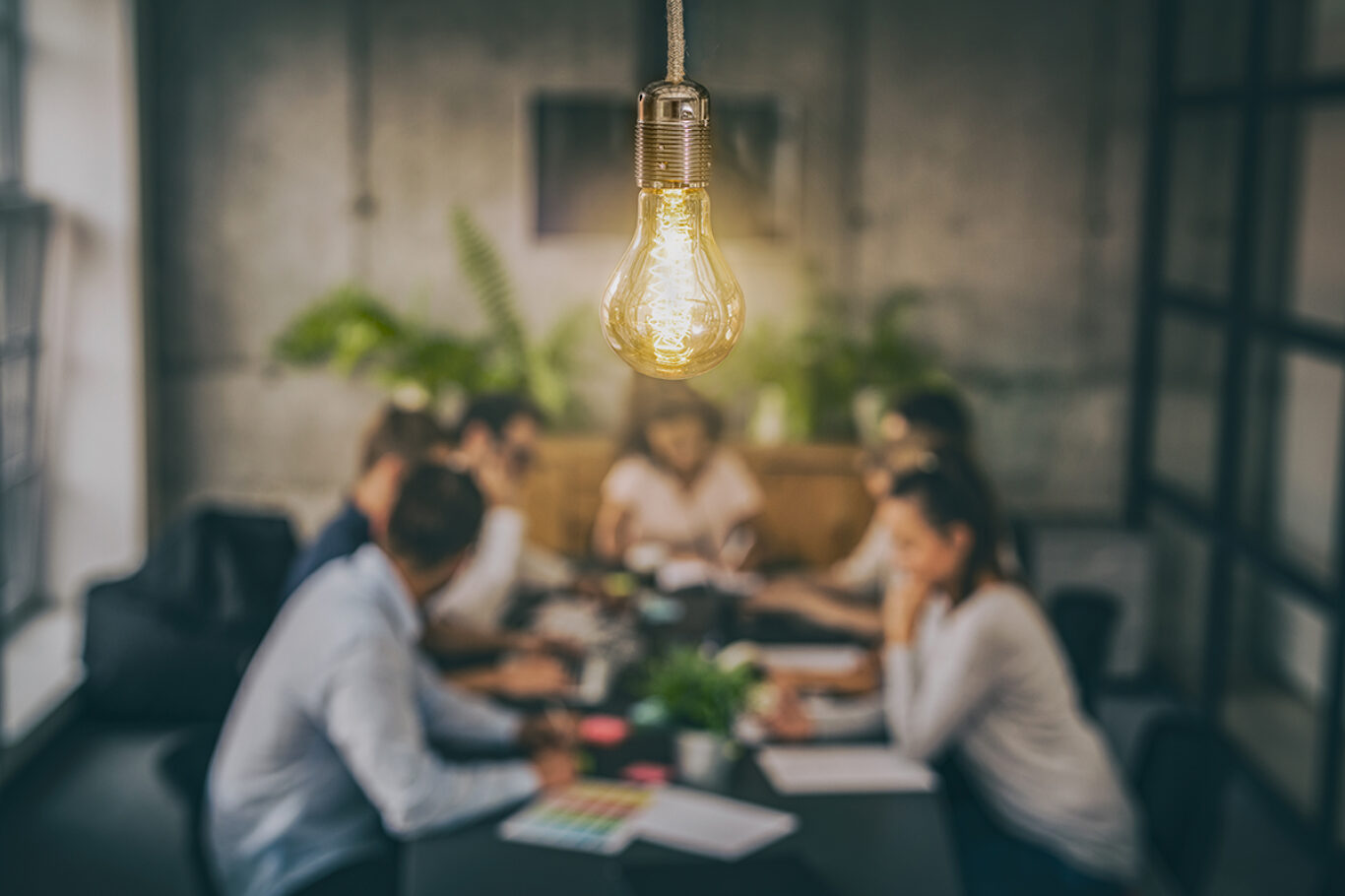 Young business people are discussing together a new startup project. A glowing light bulb as a new idea.