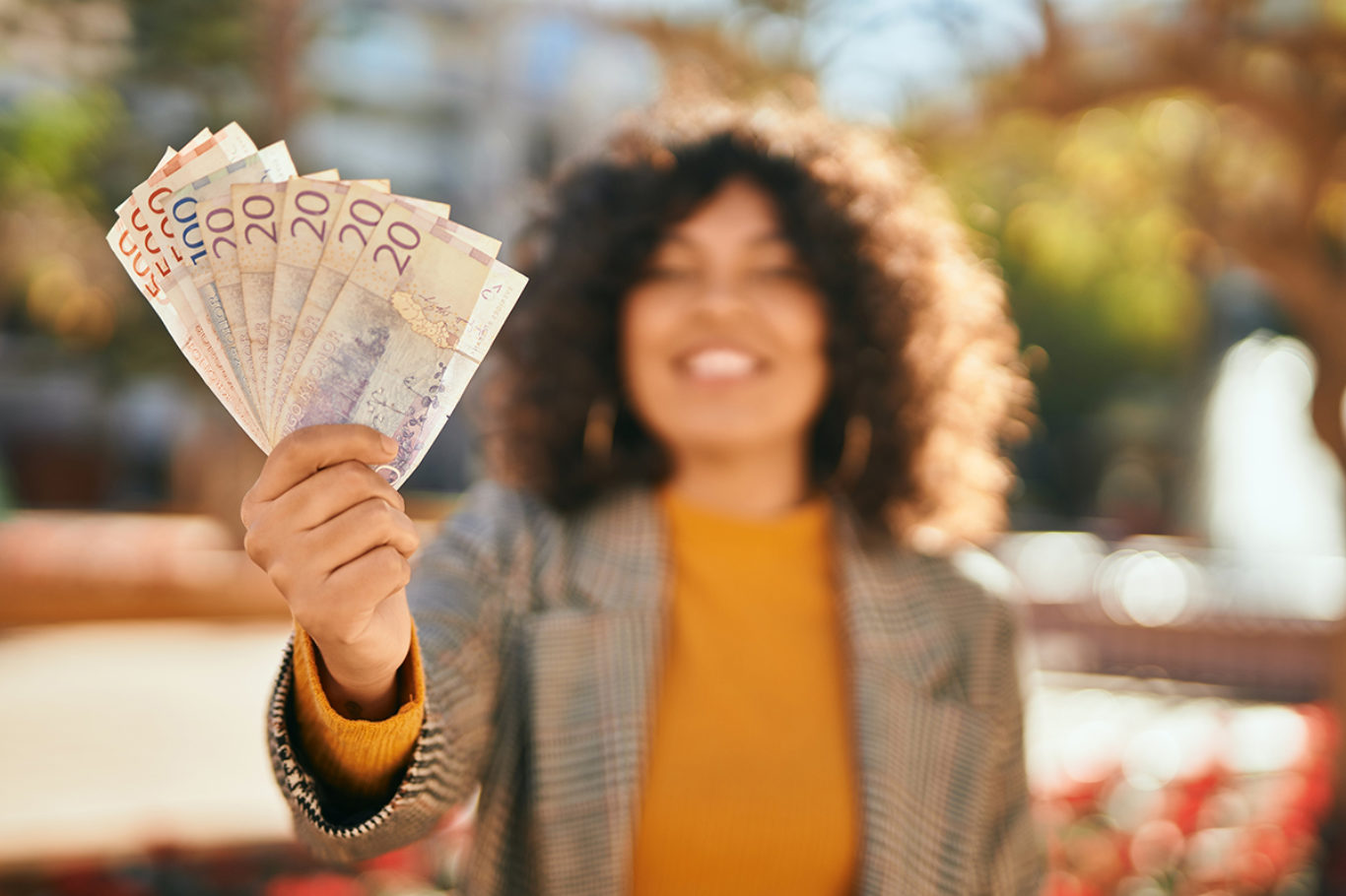 Young hispanic businesswoman smiling happy holding swedish krone banknotes at the city.