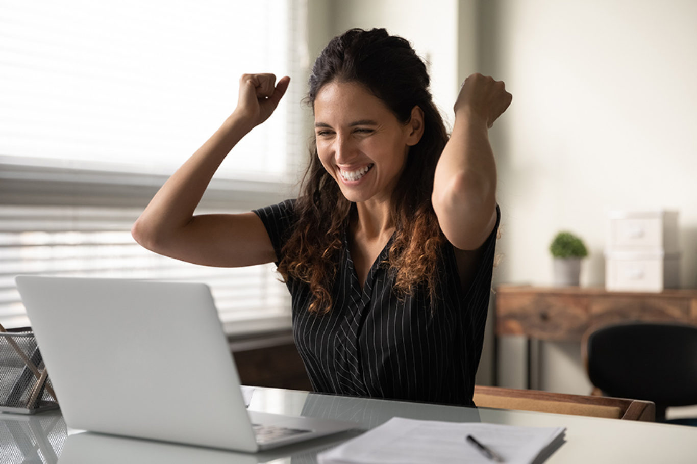 Happy excited millennial businesswoman in casual excited with good news at laptop, looking at screen, celebrating win, achieve, approved loan, making yes hand gesture. Employee getting job promotion.